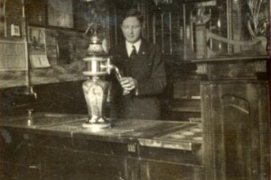 Bufet restauracyjny w hotelu „Eilers” – 1936 rok młody lekko uśmiechnięty mężczyzna za barem nalewa piwo z nalewaka do wysokiej szklanki