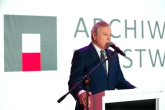 Przemawia minister Piotr Gliński na tle logo archiwów