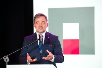 Przemawia Naczelny Dyrektor Paweł Pietrzyk na tle logo Archiwów Państwowych